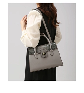 Detail of grey crocodile texture flap and gold twist-lock on a stylish crossbody bag