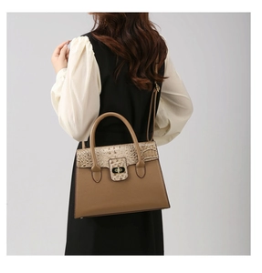 Detailed view of brown handbag with crocodile texture flap and gold swivel lock mechanism