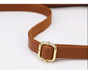Detail of adjustable brown faux leather strap with shiny gold square buckle and litchi texture