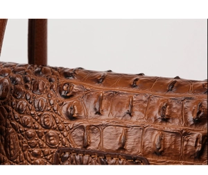 Detail shot of brown crocodile embossed leather and stitching on fashionable tote bag