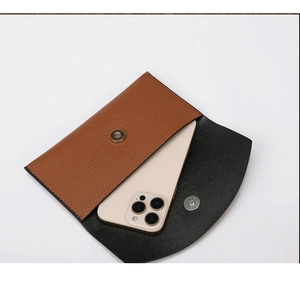 Internal capacity of brown faux leather envelope clutch shown with a smartphone