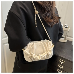 Détail du sac nuage plissé crème avec chaîne dorée et logo de la marque