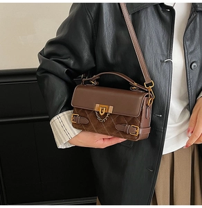 Macro view of brown quilted crossbody bag with golden chain lock and vintage hardware