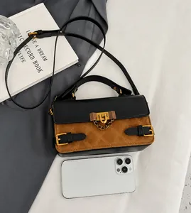 Detail of two-tone crossbody bag featuring brown quilted suede and black leather stitching