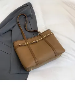 Detail view of brown faux leather tote bag with lychee texture and metallic rivets