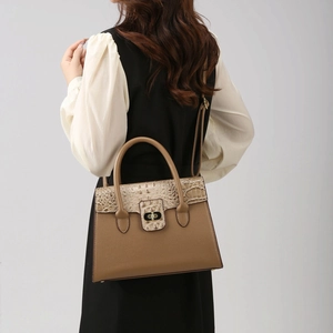 Brown faux leather tote bag with crocodile texture and gold lock shown on model