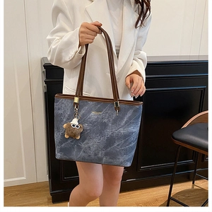 Détail du sac cabas bleu marbré avec anses en cuir marron et breloque peluche