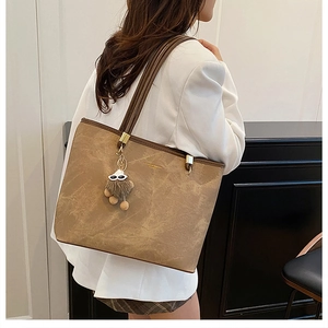 Sac fourre-tout marron à texture marbrée et charm en peluche sur un blazer blanc