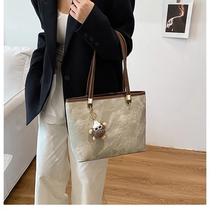 Détail du sac cabas à motif marbre avec lanières brunes et pendentif ours mignon