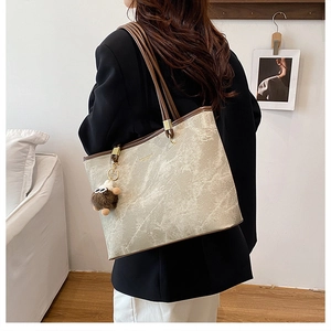 Détail du sac cabas beige texture marbre avec bordure marron foncé et breloque en peluche