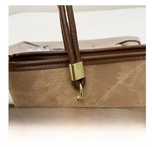Détails de la texture en toile, des ferrures dorées et des poignées en cuir sur ce cabas