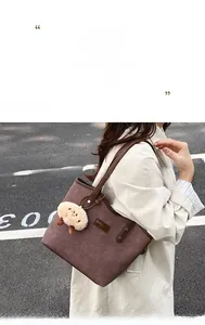 Detail of brown woven tote bag with leather handles and white lamb plush charm pendant