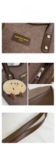 Detail view of brown tweed tote bag with leather trim, fashion logo, and plush pendant