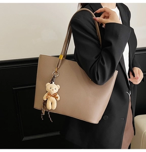 Taupe pebbled leather tote bag with a cute teddy bear charm shown on a female model