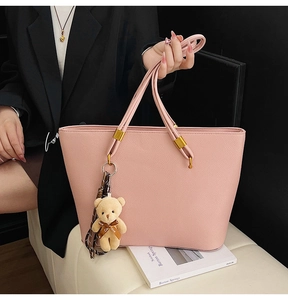Detail of pink tote bag with lychee texture leather, gold hardware, and bear pendant decor