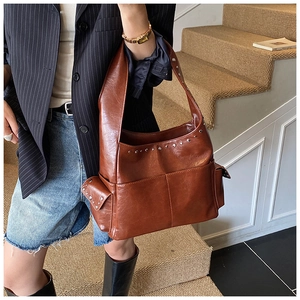 Detail showing vintage brown leather shoulder bag with silver rivet studs and side pockets