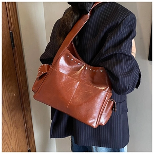 Detail of dark brown leather hobo bag with silver rivets and side pocket on shoulder