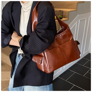 Detail of vintage brown tote bag with silver rivets on textured faux leather material