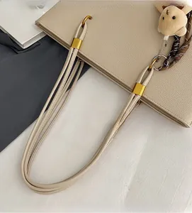Detail of off-white lychee leather tote bag with gold metal hardware and bunny charm
