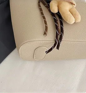 Detailed close-up of beige lychee texture leather bag with anti-slip bottom studs