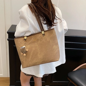 Sac cabas marron vintage en simili cuir avec pompon porté sur une veste de blazer