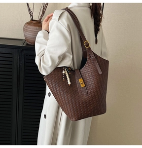 Détail du sac seau marron foncé avec texture tissée et breloque rétro en perles de bois
