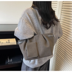 Detail of a large suede tote bag with a hanging zip pouch and side buckle on the shoulder