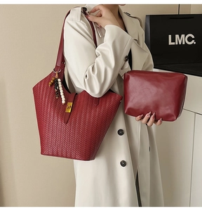 Détail d'un sac seau rouge tressé avec pochette assortie, boucle en cuir et perles
