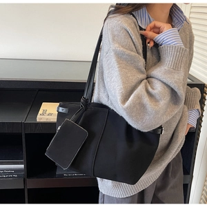 Detailed side view of a large black tote bag with a matching small zipper pouch attached