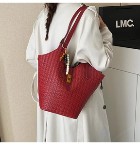 Détail du sac hobo bordeaux à texture tissée avec pendentif perlé sur la bandoulière
