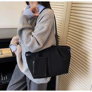 Close-up of black suede tote bag with matching zippered pouch and sleek thin shoulder straps