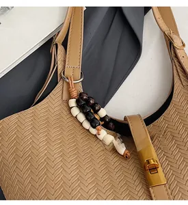 Détail du sac seau tressé avec fermoir doré et pendentif en perles colorées