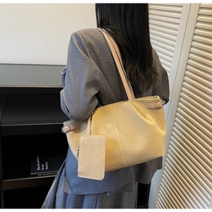 Detail of a large beige suede tote bag with matching zippered pouch on a female model