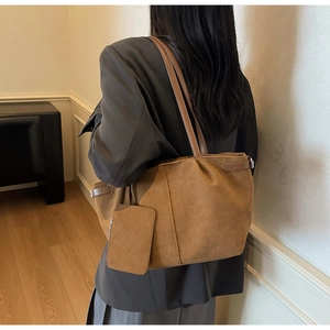 Deep brown suede tote bag with matching pouch shown on shoulder in a minimalist room
