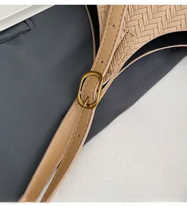 Détail de la boucle dorée réglable et de la texture tressée du sac à main en cuir