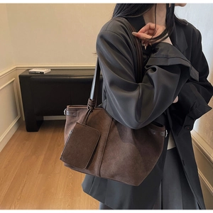 Detail view of large dark brown suede tote bag with decorative side buckle and pouch