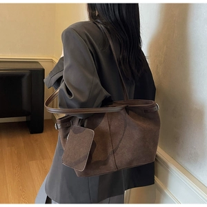 Detail view of large dark brown suede tote bag featuring adjustable side straps and mini pouch