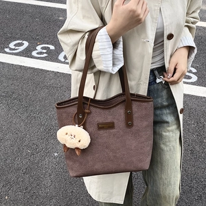 Brown woven tote bag with leather handles and sheep charm shown in outdoor style