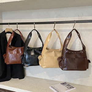 Retro rivet tote bags in multiple colors hanging on a rack with a minimalist backdrop