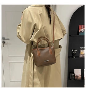 Sac à bandoulière en cuir marron porté par un mannequin en trench-coat beige classique
