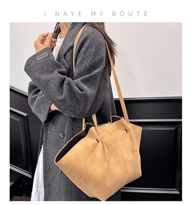 Detail shot of large camel suede tote bag showing soft pleated texture and shoulder strap