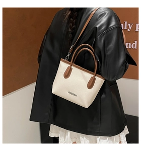 Détail du sac seau bicolore en cuir grainé avec bandoulière amovible élégante