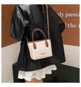 Detail of cream-white pebble grain leather bucket bag with brown adjustable shoulder strap