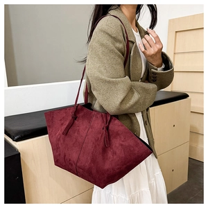 Detail of burgundy faux suede tote bag featuring a spacious interior and minimalist shoulder strap