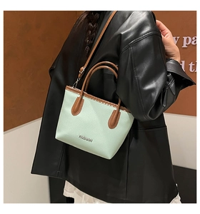 Detail of mint green lychee grain leather tote with silver FASHION metal logo and brown trim