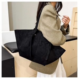 Close-up of matte black suede tote bag featuring long straps and minimalist side tie detail
