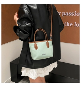 Détail du sac cabas en cuir vert menthe et marron montrant la bandoulière et le grain