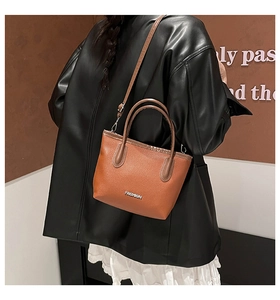 Gros plan d'un sac à main en cuir marron avec l'inscription métallique FASHION