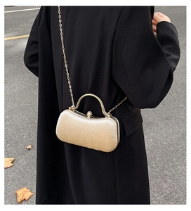 Detail of champagne gold evening clutch with pearl clasp and metallic top handle