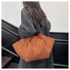 Detail of caramel suede tote bag with knotted side accents and slender shoulder strap
